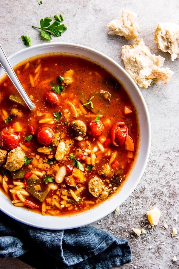 white soup plate filled with slow cooker tuscan white bean and sausage soup