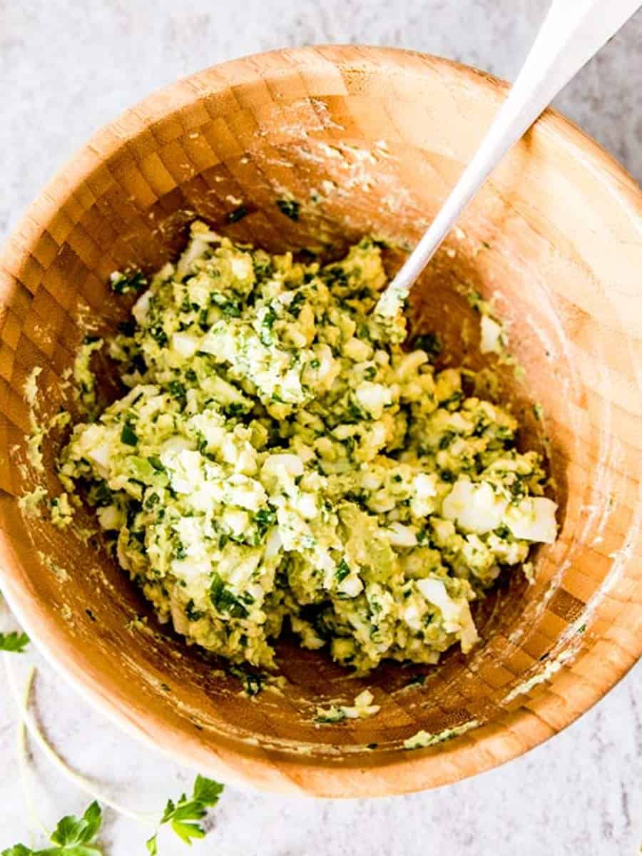 overhead view of wooden bowl filled with avocado egg salad