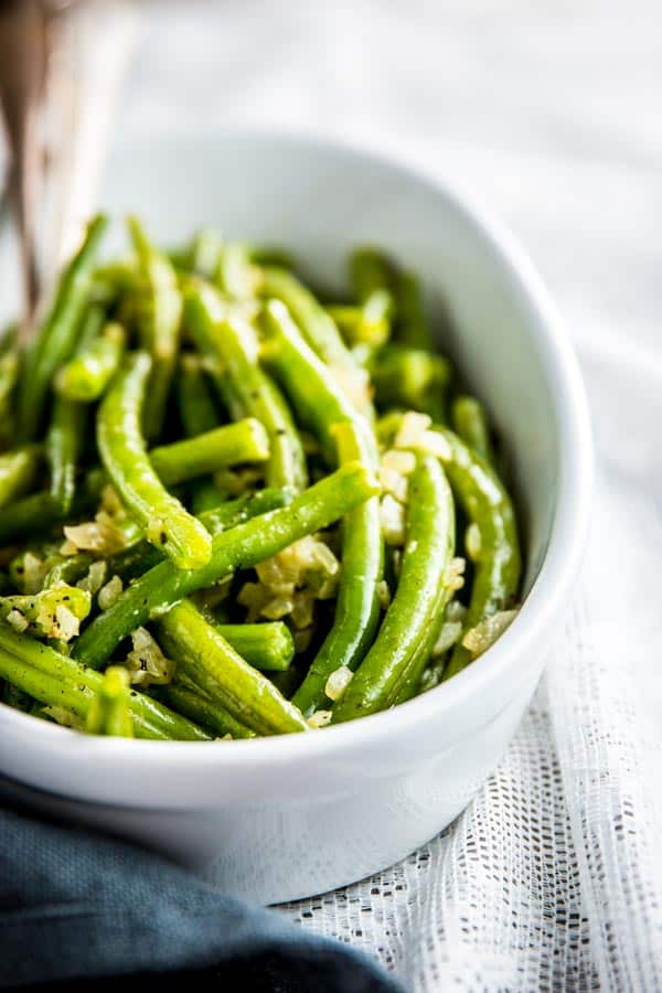 green beans with diced onion in white dish