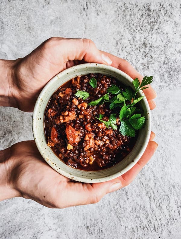 female hands holding bowl with cooked lentils