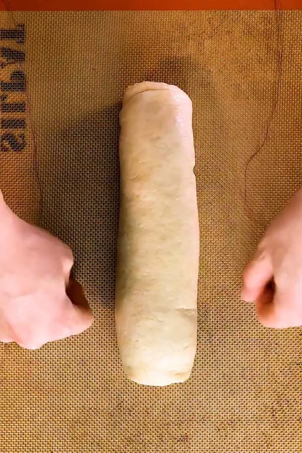 cutting a log of dough into cinnamon rolls with a pice of string - 1