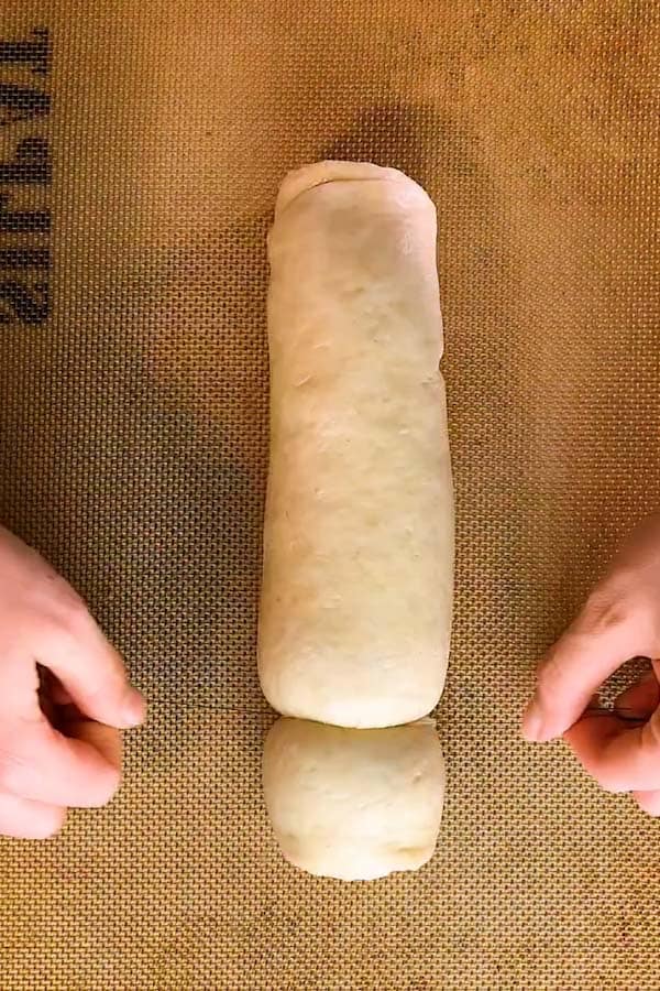 cutting a log of dough into cinnamon rolls with a pice of string - 3