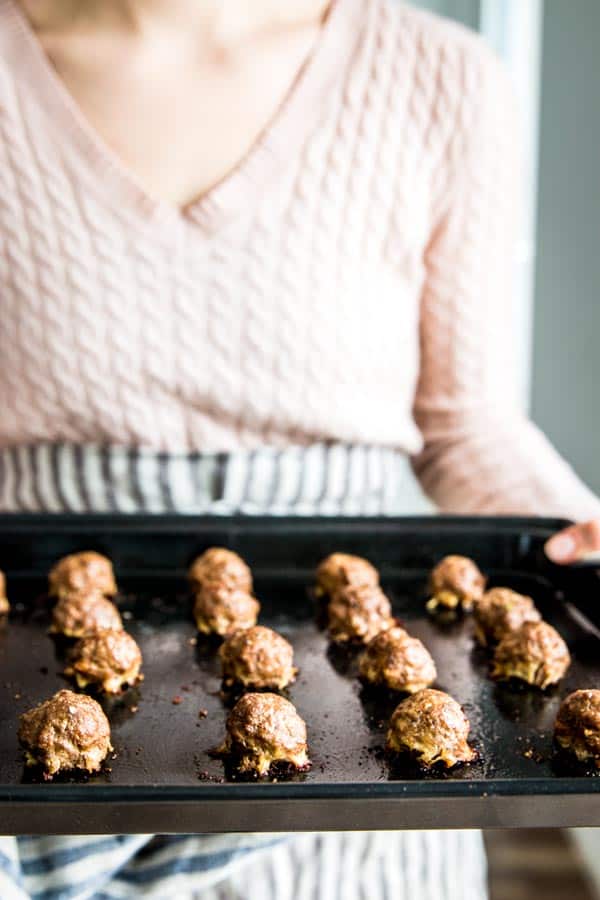 Holding oven baked meatballs on a tray.