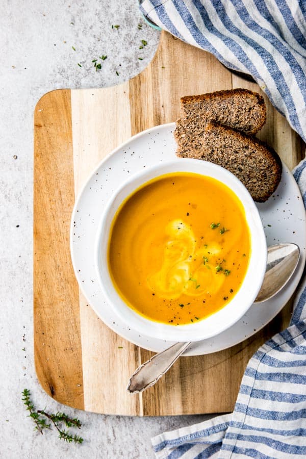 pumpkin soup in white bowl on wooden board