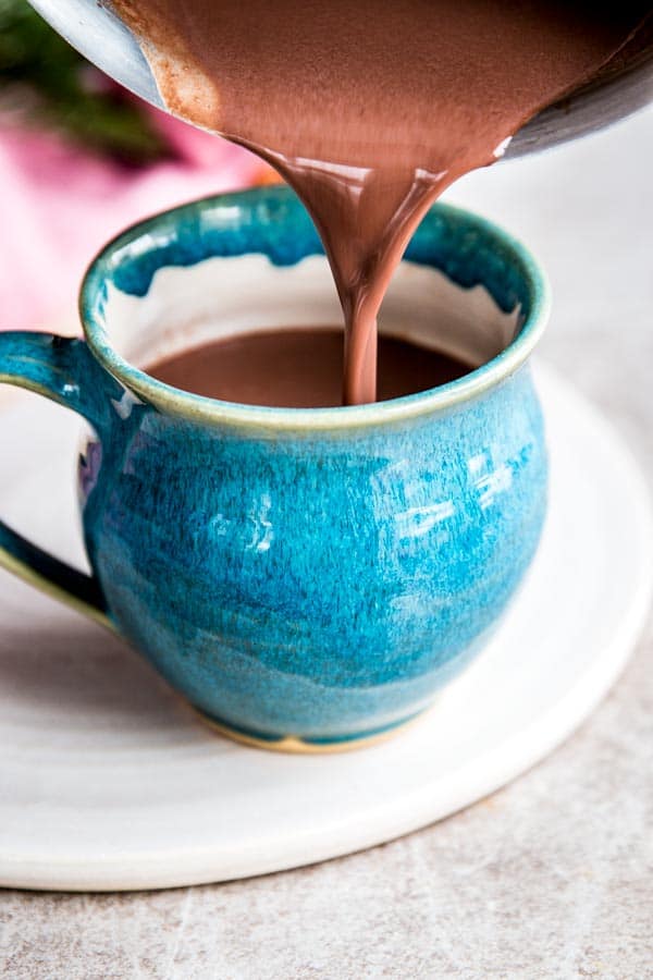 Pouring homemade hot chocolate into a pottery mug.