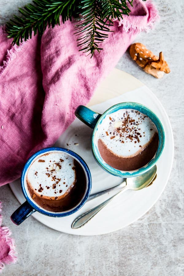 Two mugs of hot chocolate in a Christmas scene.