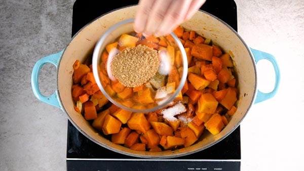 Adding brown sugar to pumpkin soup.