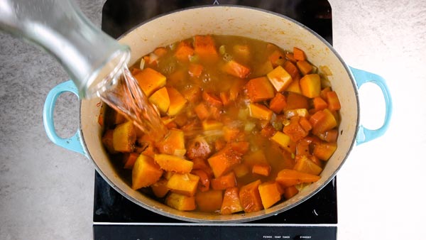 Pouring water over the vegetables for easy pumpkin soup.