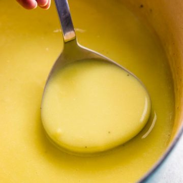 close up photo of ladle with potato leek soup in Dutch oven