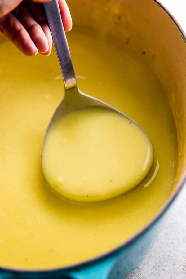 close up photo of ladle with potato leek soup in Dutch oven