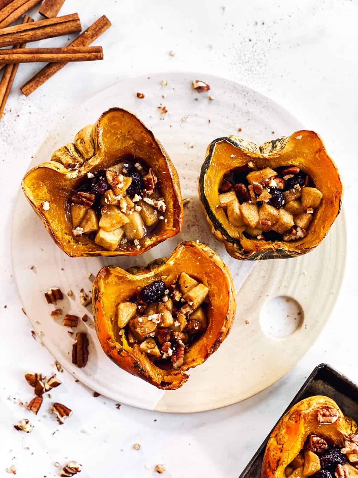 three stuffed acorn squashes on a white platter