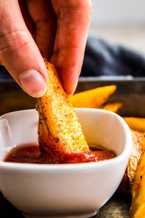 Dipping baked potato wedges in ketchup