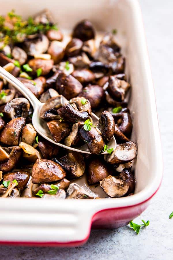 Garlic Butter Mushrooms in a casserole dish with a spoon.