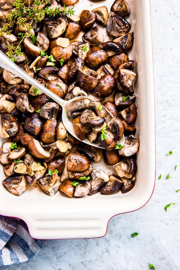 Garlic Butter Mushrooms in a Le Creuset casserole dish with a spoon.