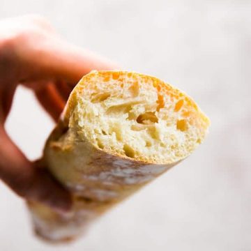 Holding a sliced homemade French bread.