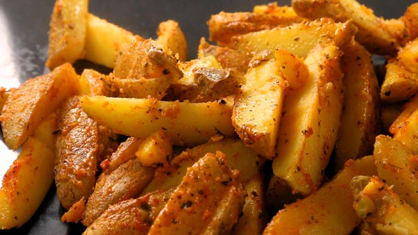 Placing baked potato wedges on preheated baking sheet