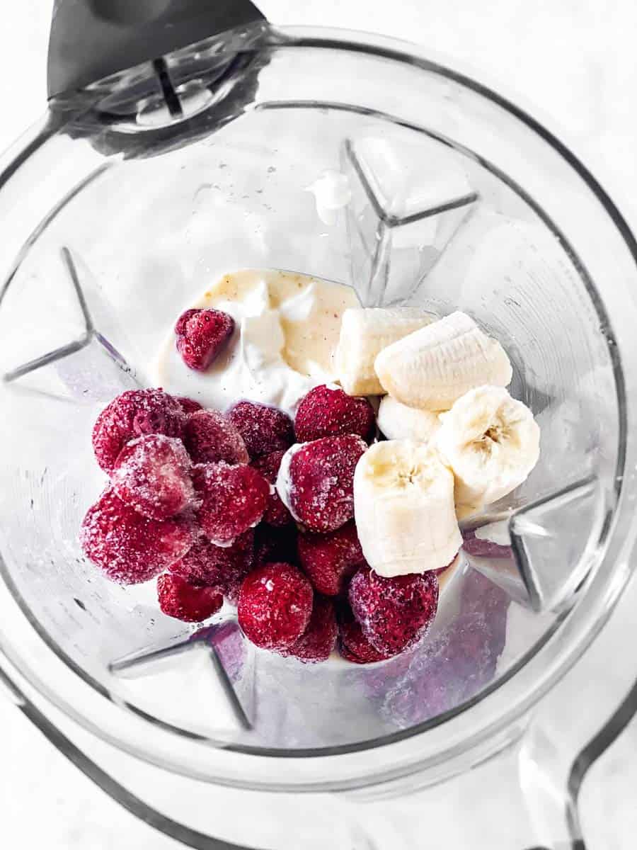 blender with ingredients for a strawberry banana smoothie