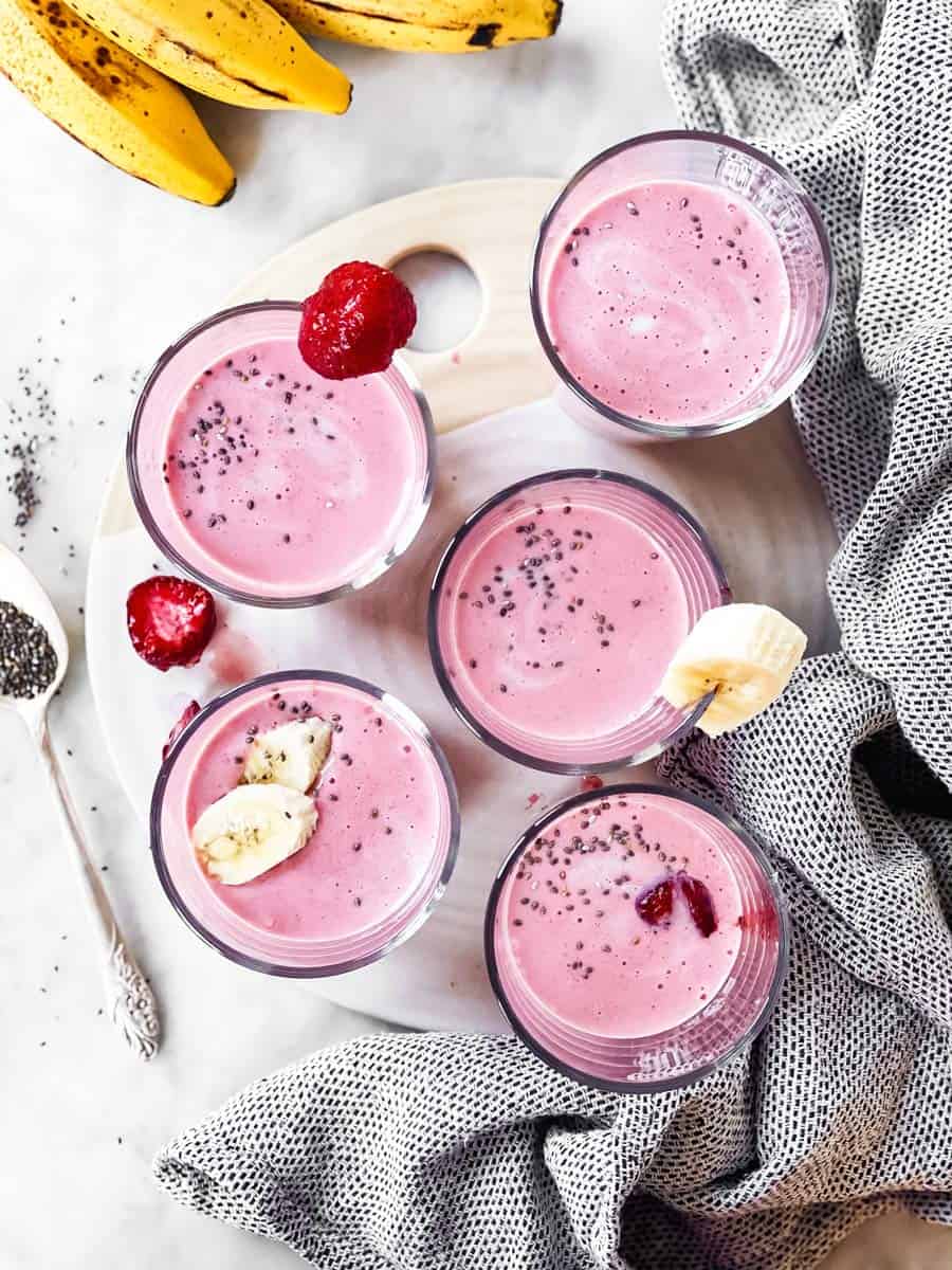 overhead view of several glasses with banana strawberry smoothie