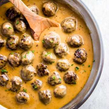 Serving easy Swedish meatballs from the skillet with a wooden spoon.
