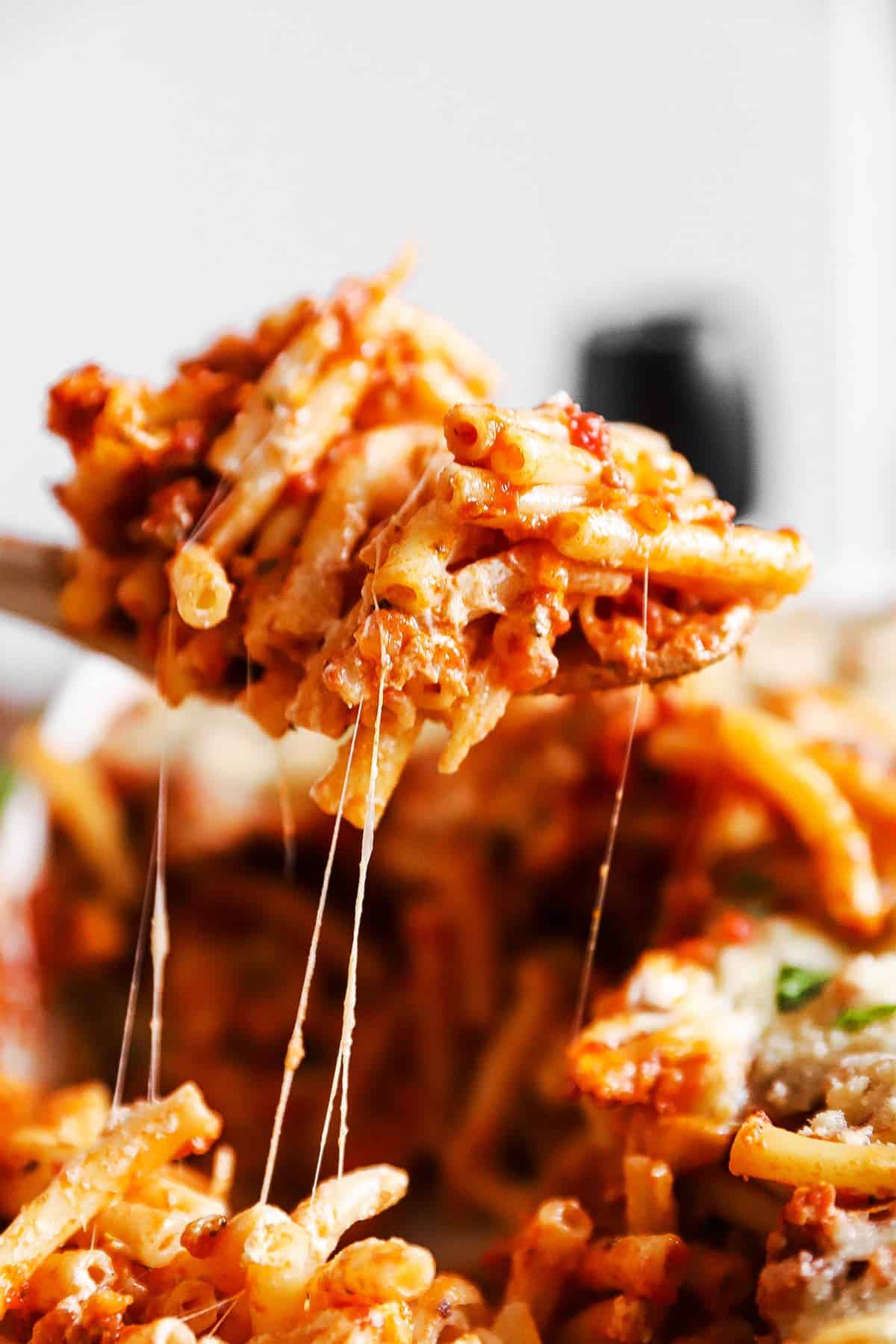 scooping baked ziti from casserole dish