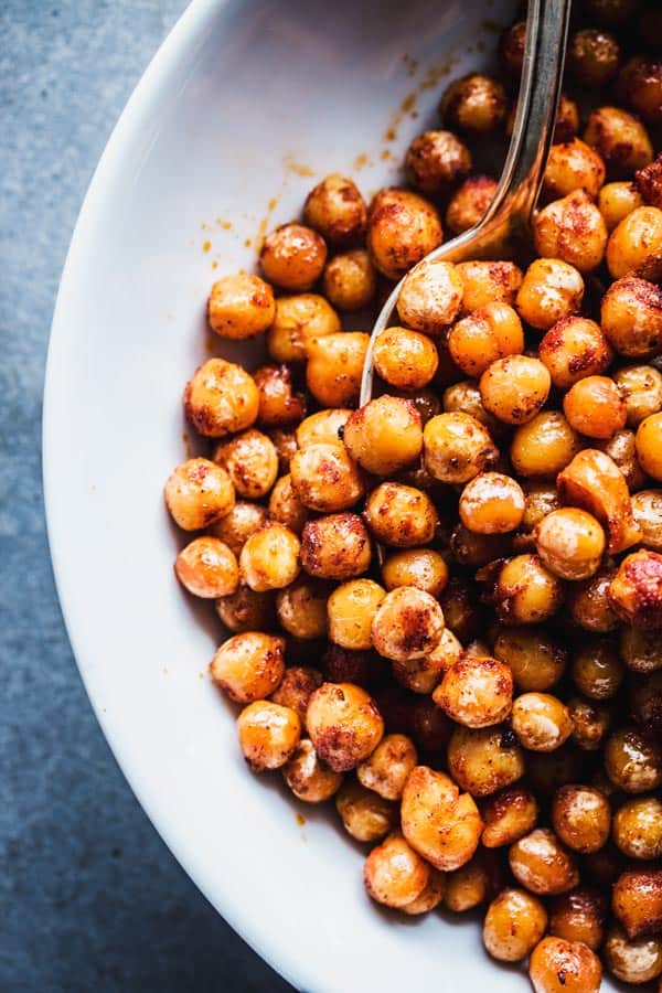 Close up of smoked paprika chickpeas on a white plate with a spoon.
