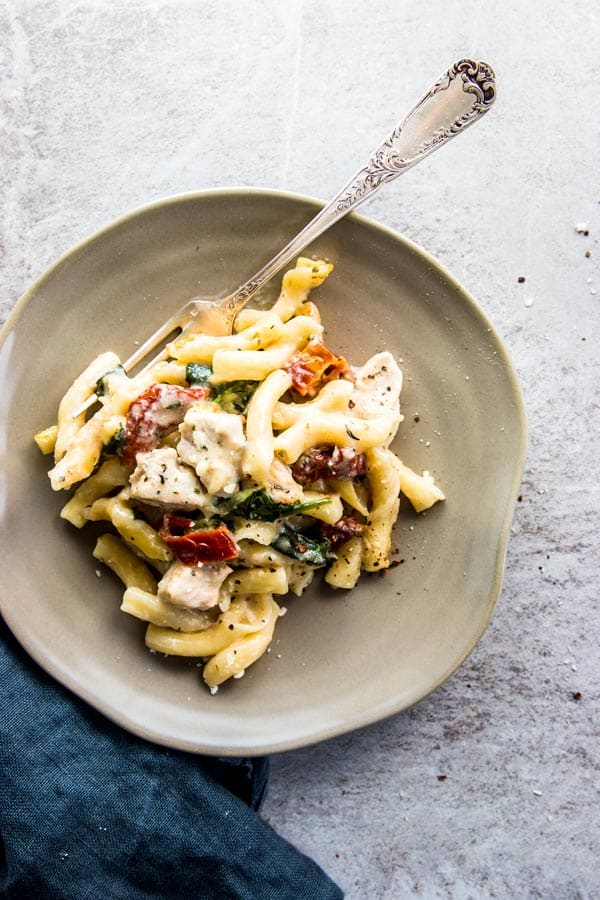 Chicken Florentine Pasta Casserole on a grey plate with a silver fork and a black napkin.