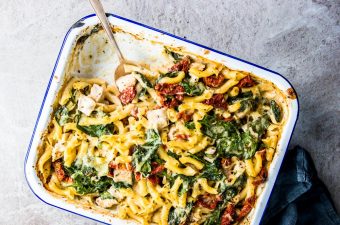 Chicken Florentine Pasta Casserole in a enamel casserole dish with a silver spoon.