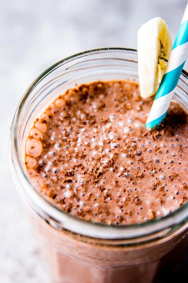 Chocolate peanut butter banana smoothie in an empty jam jar, sprinkled with grated dark chocolate 