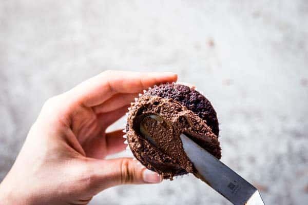 Spreading easy chocolate frosting on a chocolate cupcake.