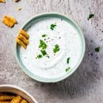 Bowl of ranch dip with chips around it.