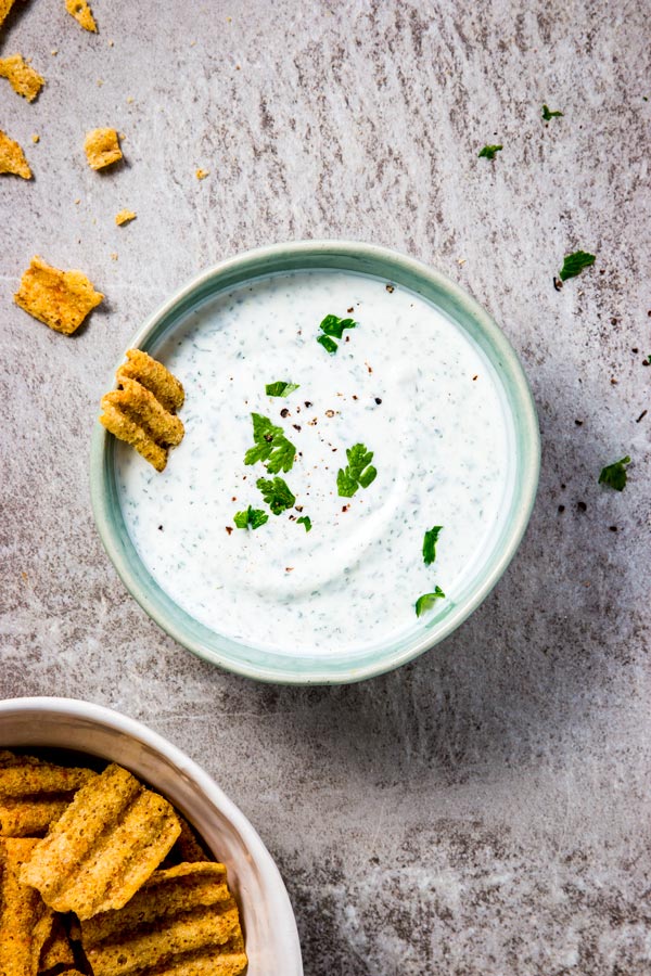 Bowl of ranch dip with chips around it.