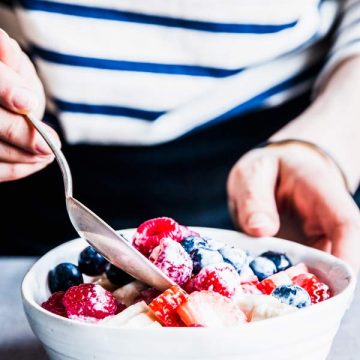 Mixing berries, banbana and Greek yogurt dressing for Banana Triple Berry Fruit Salad.