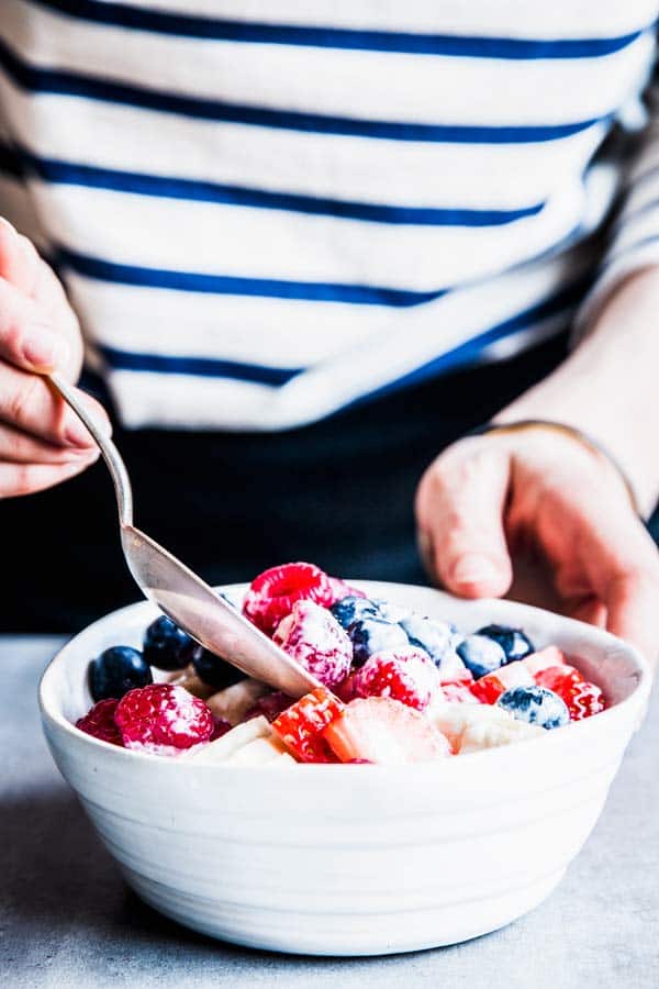 Mixing berries, banbana and Greek yogurt dressing for Banana Triple Berry Fruit Salad.