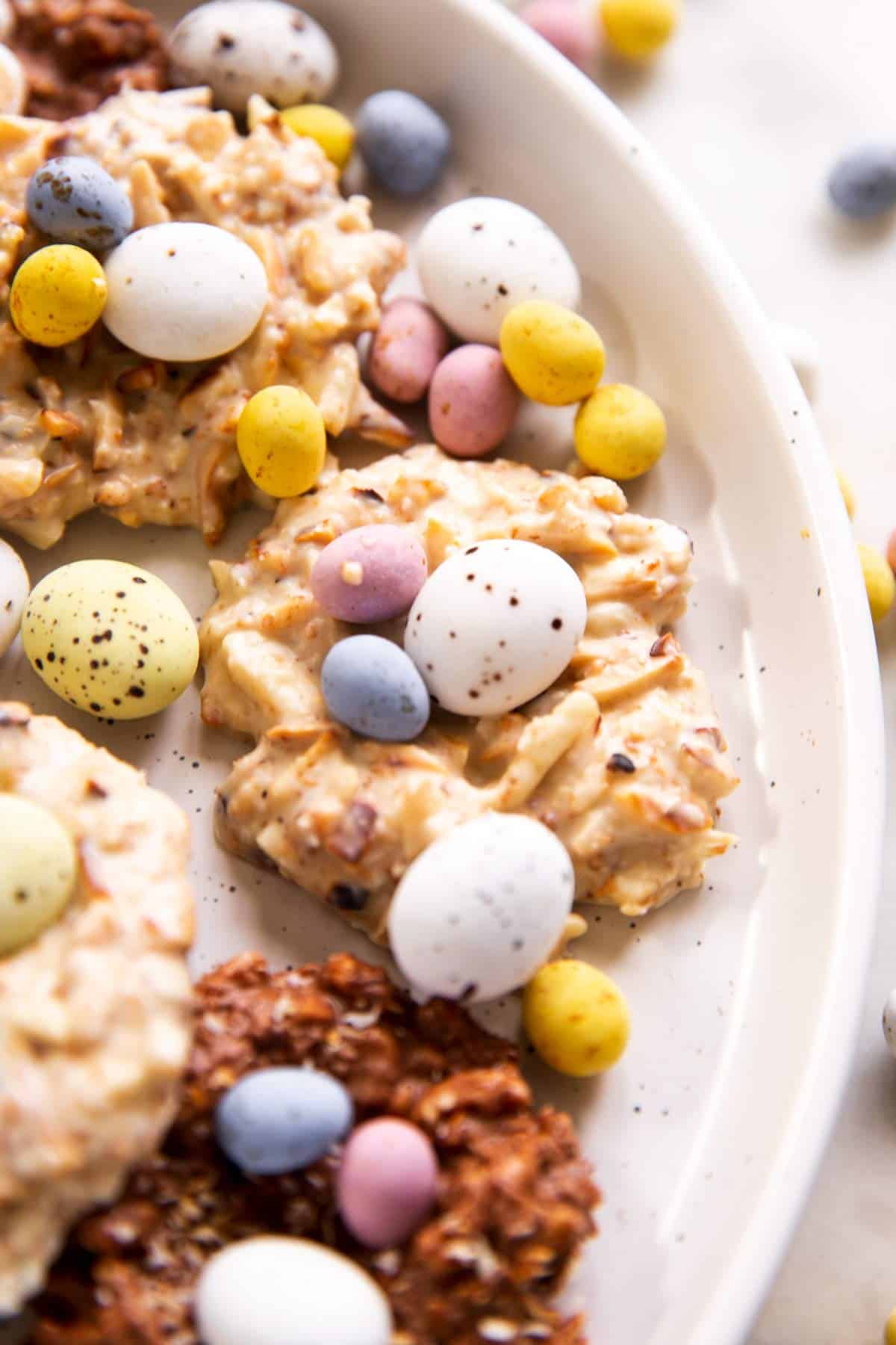 close up photo of white chocolate Bird's nest cookie on plate with several mini eggs and more cookies in background