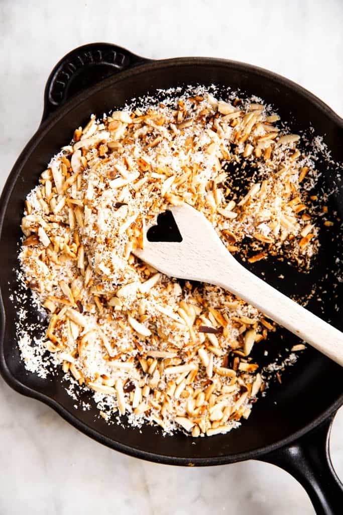 toasted almonds and shredded coconut in black cast iron skillet