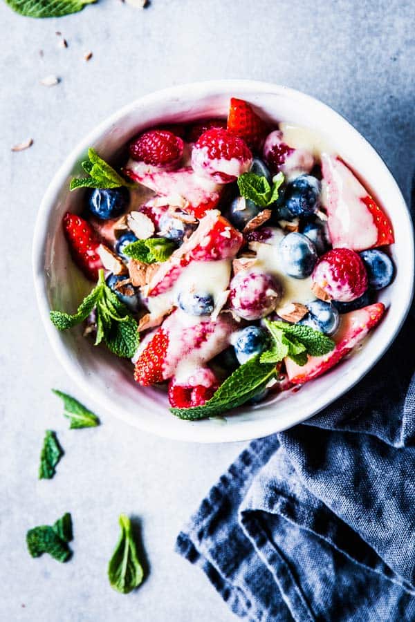 Berry Cheesecake Fruit Salad in a white bowl on the table with a black napkin.