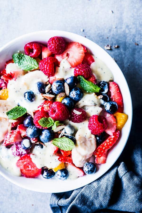 Creamy fruit salad in a white bowl with a black napkin.