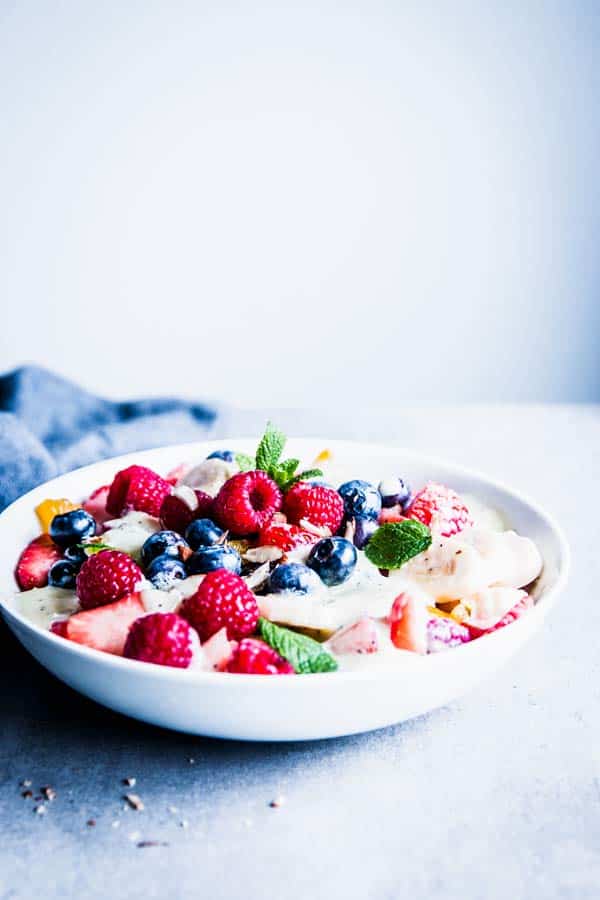 Creamy fruit salad in a white bowl on the table.