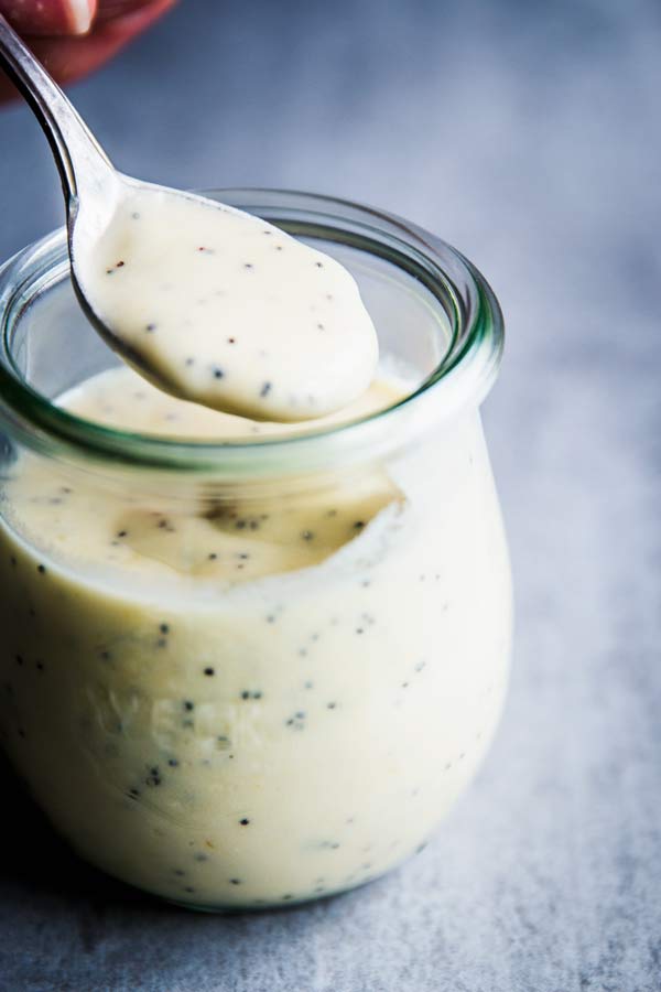Spooning creamy poppy seed fruit salad dressing from a small weck jar.