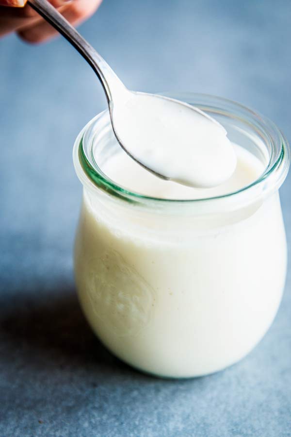 Spooning Greek Yogurt Fruit Salad Dressing out of a small weck jar.