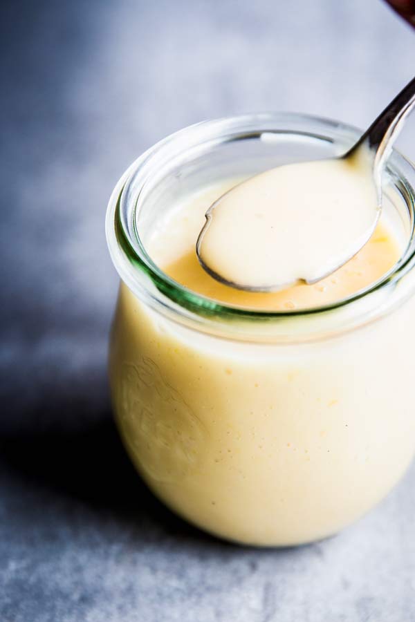 Spooning creamy fruit salad dressing out of a weck jar.