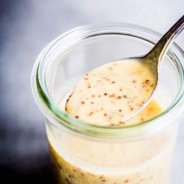 Spooning Honey Mustard Salad Dressing out of a glass jar.