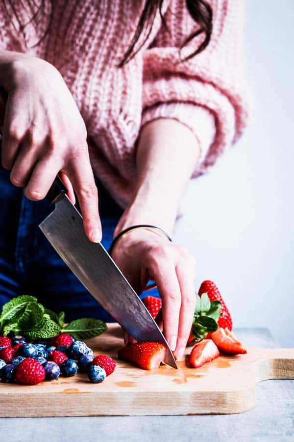 Woman slicing strawberries for a fruit salad.