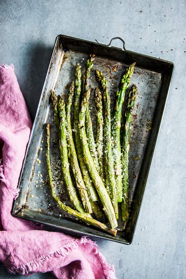 Parmesan Roasted Asparagus on a metal sheet pan with a pink napkin.