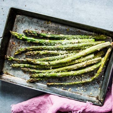 Garlic Parmesan Roasted Asparagus on a sheet pan, next to a pink napkin.