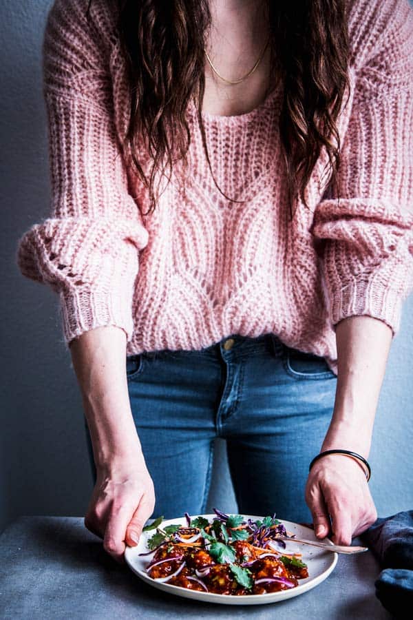 Woman in a pink sweater serving a plate of Pineapple BBQ Meatballs.