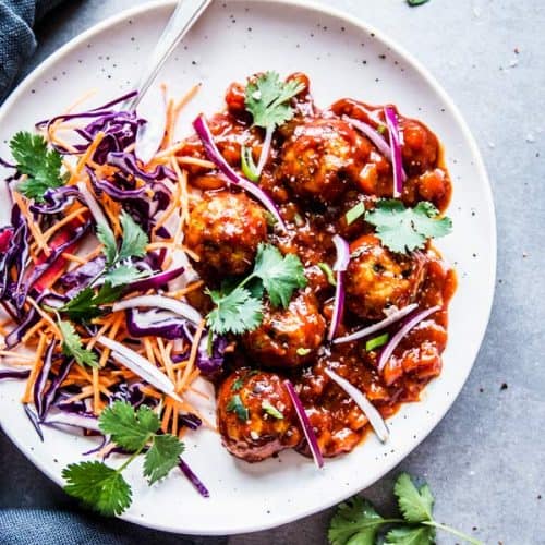 Pineapple BBQ Meatballs on a white plate with slaw and cilantro.