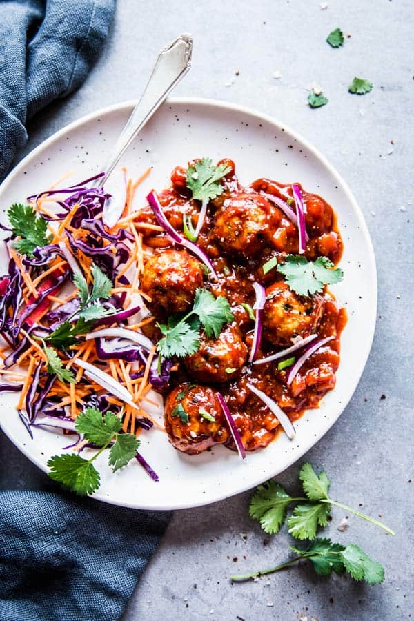 Pineapple BBQ Meatballs on a white plate with slaw and cilantro.