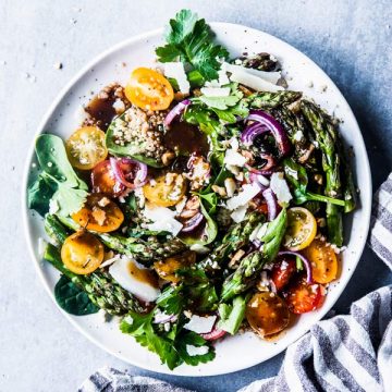 Quinoa Spinach Salad with Asparagus on a white plate with a striped linen.