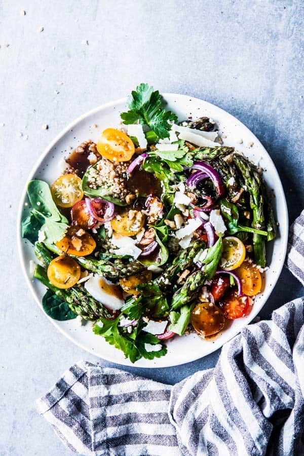 Quinoa Spinach Salad with Asparagus on a white plate with a striped linen.